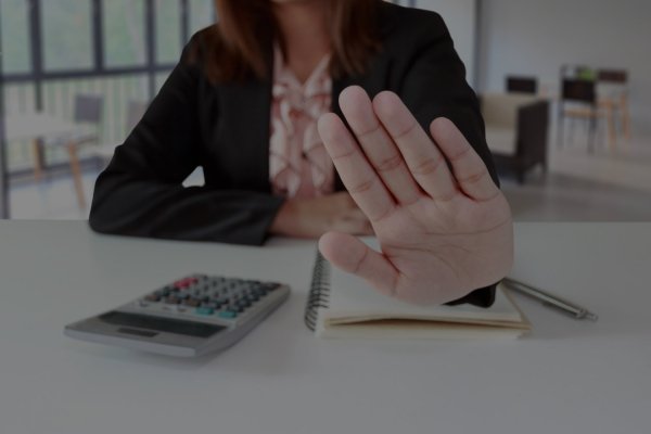 Empleado del banco rechazando una solicitud de subrogación de hipoteca con la mano en señal de negativa