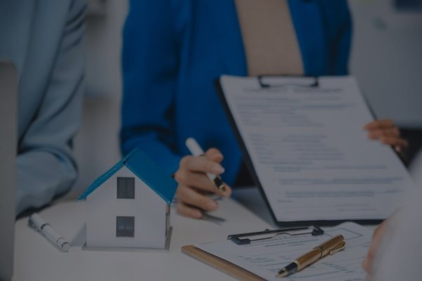 Firma de un contrato de reserva de vivienda junto a una maqueta de casa